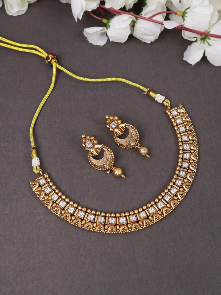 Classic 18K Gold Plated Temple Necklace - by Live Some India in just A closeup image of Classic 18K Gold Plated Temple Necklace - 4 by Live Some India on a grey background with flowers