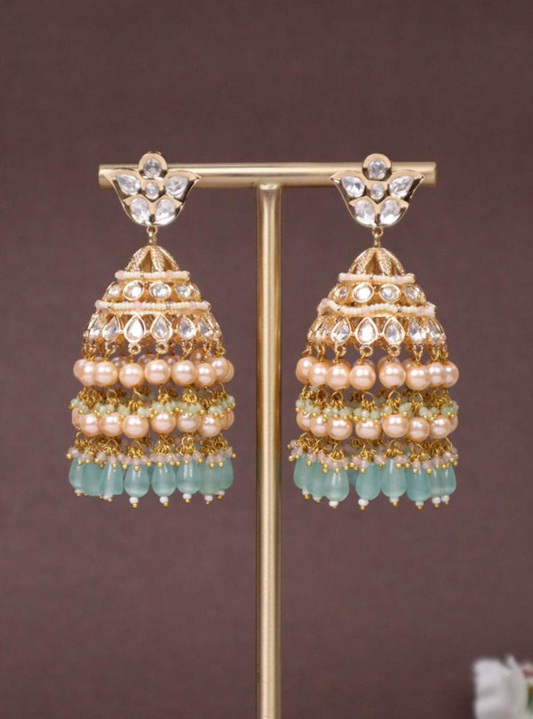 Idah Kundan Polki Jhumka Earrings - by Live Some India in just A closeup image of Idah Mint Green Kundan Polki Jhumka Earrings -1 on an earring stand with a brown background and white flowers