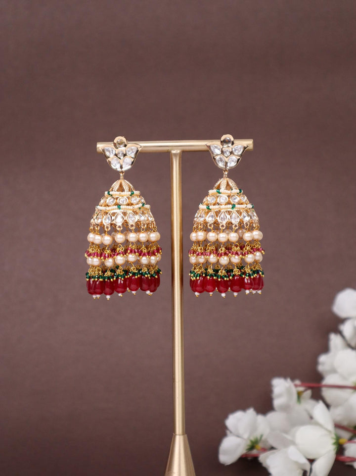 Idah Kundan Polki Jhumka Earrings - by Live Some India in just A closeup image of Idah Red Kundan Polki Jhumka Earrings -1 by Live Some India on an earring stand with a brown background and white flowers