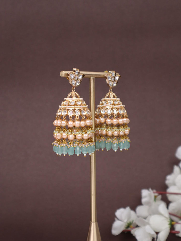 Idah Kundan Polki Jhumka Earrings - by Live Some India in just A closeup image of Idah Mint Green Kundan Polki Jhumka Earrings -2 by Live Some India on an earring stand with a brown background and white flowers